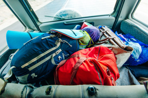 游客把背包放在汽车后备箱里。为旅行做准备。旅游或开车旅行的概念。图片下载