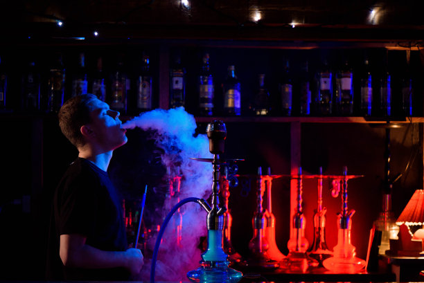 在水烟咖啡馆吸传统水烟并吐烟的男人图片下载