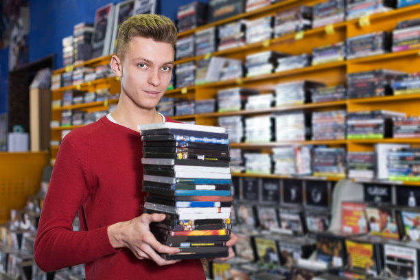 拿着一堆装着dvd的盒子的人图片下载