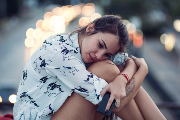 沮丧的年轻女子坐在桥的栏杆上图片下载