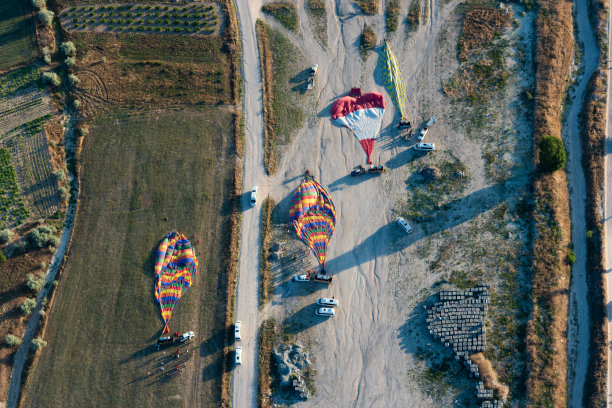 空中拍摄的热气球在飞行后落在地面上。卡帕多西亚,土耳其。图片下载