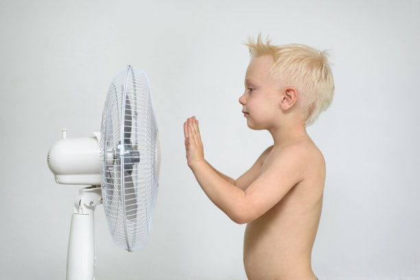 一个全身赤裸、双手朝天的金发小男孩站在呼吸机旁。夏天的概念图片下载