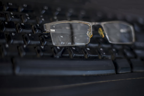 黑色的半框眼镜或眼镜在黑色的桌面键盘上。图片下载