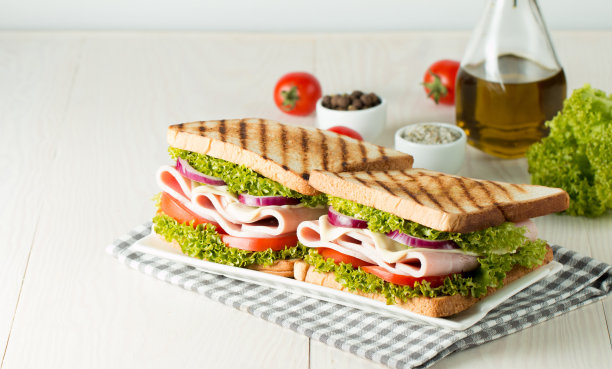 俱乐部三明治的特写照片。三明治与肉，火腿，意大利腊肠，沙拉，蔬菜，生菜，番茄，洋葱和芥末在新鲜的黑麦面包切片在木制背景。橄榄背景。图片下载