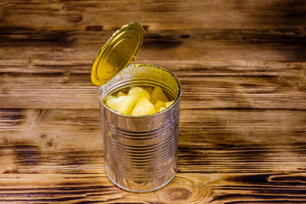 铝锡罐和切碎的菠萝罐头放在木桌上图片下载