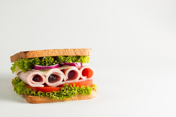 俱乐部三明治的特写照片。三明治与肉，火腿，意大利腊肠，沙拉，蔬菜，生菜，番茄，洋葱和芥末在新鲜的黑麦面包切片在木制背景。橄榄背景。图片下载