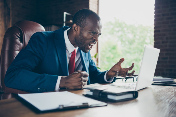 深色皮肤的家伙在skype沟通表达愤怒的照片穿着优雅的服装坐在办公椅图片下载