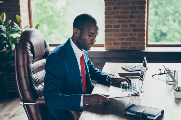 照片中的深色皮肤的家伙发短信笔记本阅读纸穿优雅的服装坐在办公椅图片下载