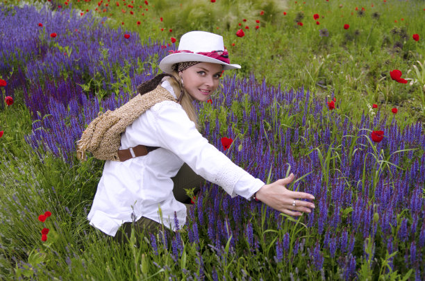 在草地上拥抱薰衣草花的女人。图片下载