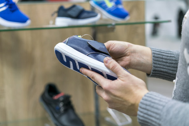 一位妇女在鞋店为她的儿子挑选运动鞋图片下载