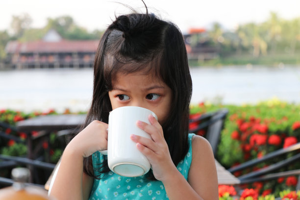 亚洲可爱的女孩拿着杯子和喝牛奶高钙的早餐奶孩子图片下载