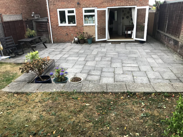 红色砖墙和开放玻璃门的现代房子的图像照片，后花园设计庭院与曲折的草坪和大不规则的天井铺路板在夏天的房子外，在枯死的草坪草坪干旱后需要水杂草饲料图片下载