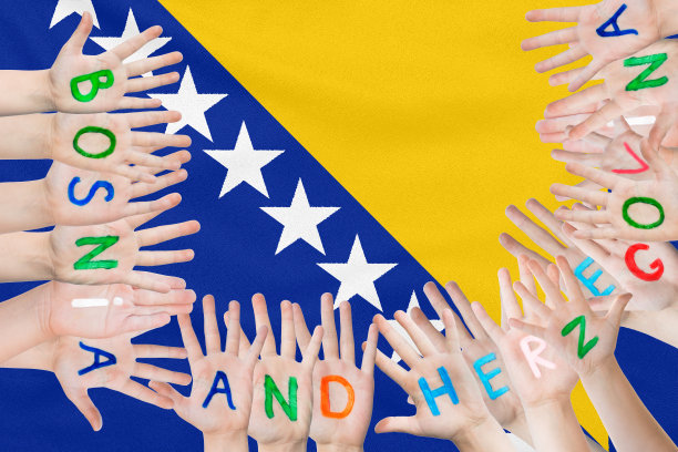 以飘扬的波斯尼亚-黑塞哥维那国旗为背景，在儿童的手上题字波斯尼亚-黑塞哥维那图片下载