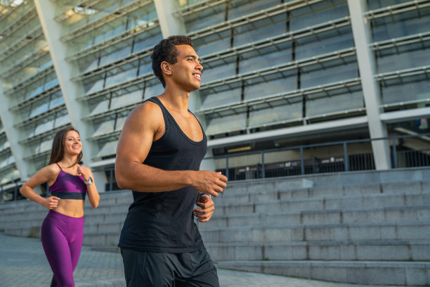 近距离的年轻夫妇在运动服装沿着城市街道一起跑步图片下载
