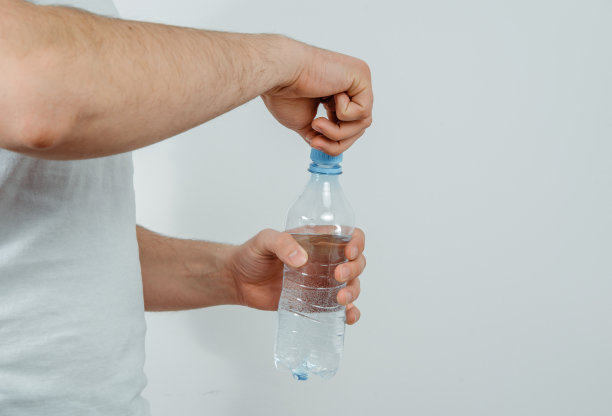 喝瓶子里的水。一个口渴的人手里拿着一瓶水。口渴的概念，渴望喝干净的水。图片下载