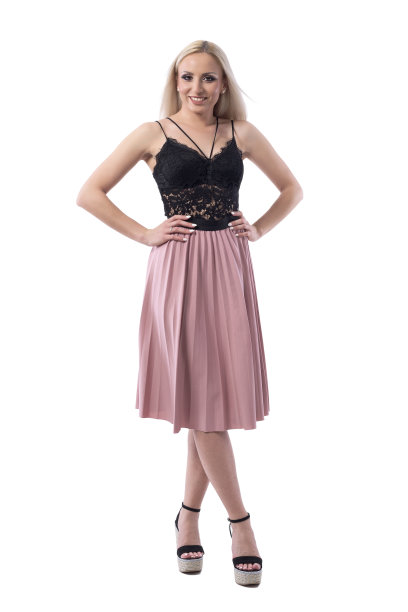 可爱的漂亮的金发女人在黑色蕾丝上衣和鲑鱼色裙子摆姿势与胳膊上的臀部。图片下载