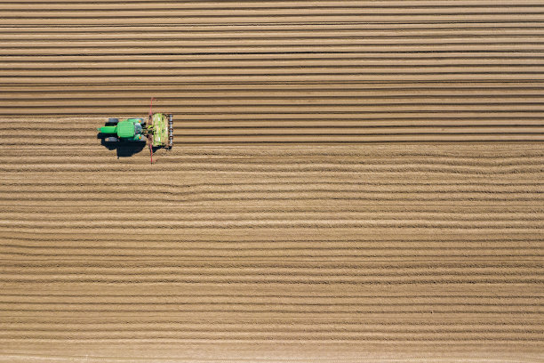 农用拖拉机在田间耕作和喷洒的鸟瞰图。农业。从以上观点。无人机拍摄的照片。图片下载