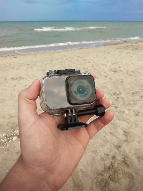 在海滩背景处按住动作摄像机。图片下载