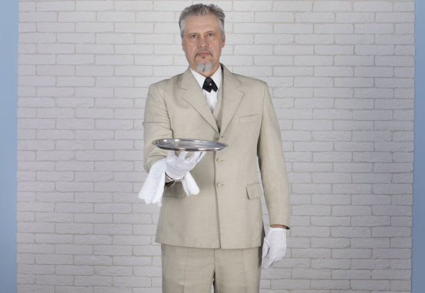 一个穿着白色西装拿着托盘的服务员的工作室肖像图片下载