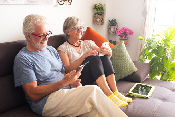 几个高级人员正在用手机和家人或朋友聊天。自然花草的背景。白头发和眼镜给两个在放松的退休老人图片下载