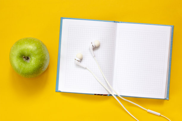 健康的生活方式。教育、研究概念。耳机，绿苹果和黄色背景的笔记本。副本的空间。图片下载