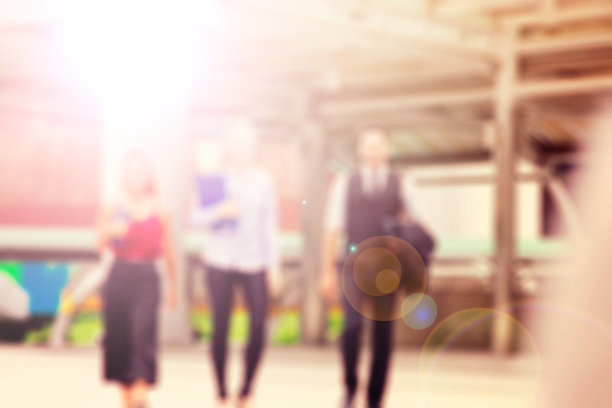 三名商务人士在建筑物外的灯光下行走和交谈的散焦照片图片下载