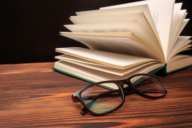 在黑色的背景上打开一本带眼镜的书。——图片图片下载