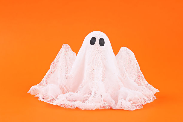 万圣节幽灵的淀粉和纱布在橙色的背景。礼物创意，万圣节装饰。图片下载