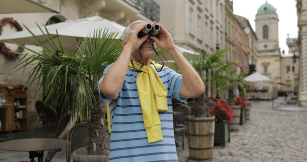 资深男游客探索城镇。旅行。在双筒望远镜图片下载
