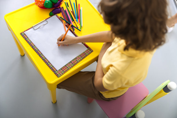 卷毛小孩用铅笔在游戏室库存照片图片下载