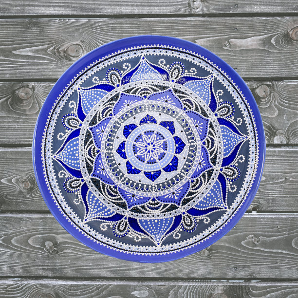 装饰陶瓷板，手工绘制点图案与丙烯酸油漆在灰色木制背景。一个正方形的照片。特写镜头。图片下载