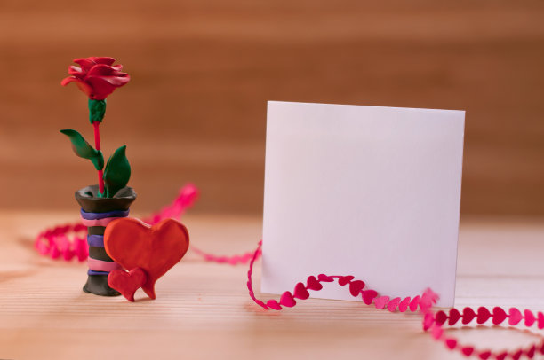 一张纸写的信息中间的心和玫瑰的橡皮泥在木桌上图片下载