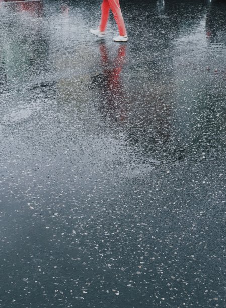 身穿红色裤子的男子背景为潮湿的沥青，阴雨天气，背景为文字图片下载