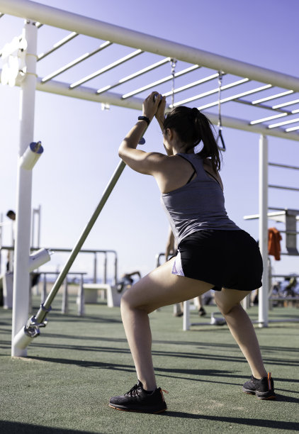 美丽的女人做下蹲与重量杆在户外训练地点或巴塞罗那街头锻炼图片下载