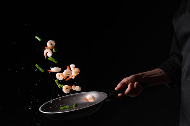 海鲜，厨师烹饪虾与球芽甘蓝和豆荚豆在煎锅，油炸。以黑色为背景进行设计，菜单、餐厅、东方料理、健康食品。水平的照片图片下载
