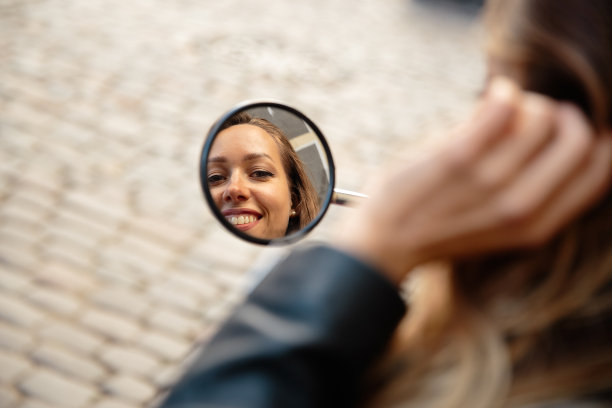 快乐微笑的女人肖像反射在镜子中的摩托车图片下载