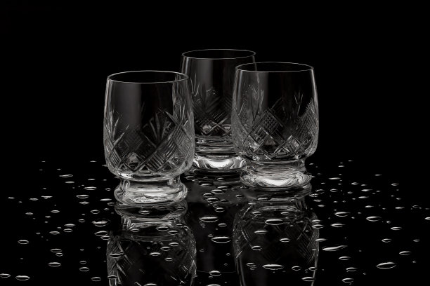 深色的吧台桌上放着三杯冷伏特加。黑色背景上的冰镇伏特加酒杯图片下载