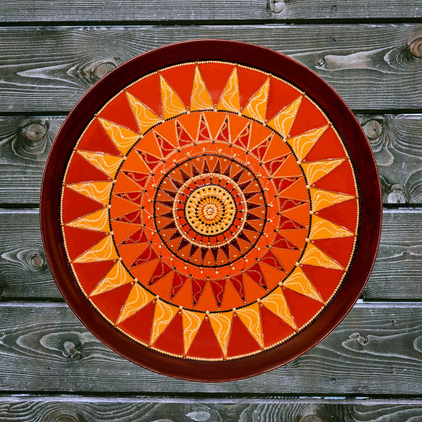 装饰陶瓷板，手工绘制点图案与丙烯酸油漆在灰色木制背景。一个正方形的照片。特写镜头。图片下载