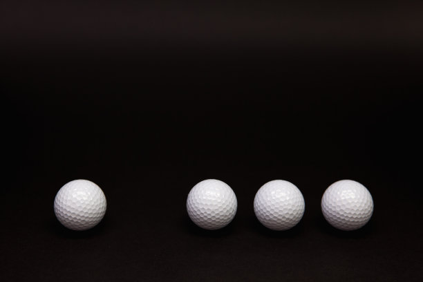 白色和橙色的高尔夫球放在黑色的桌子上。图片下载
