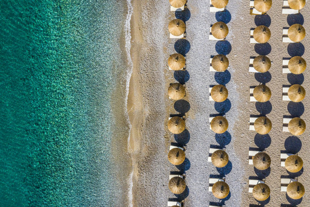 海滩的海岸线上点缀着雨伞图片下载