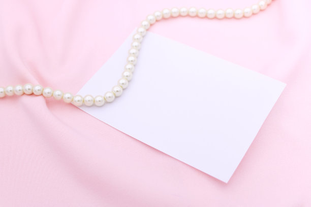 珍珠项链上的粉色织物与纸纸条。图片下载