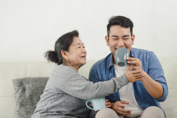 亚洲母亲和她的儿子在家里聊天和喝酒，生活方式的概念。图片下载