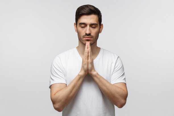 年轻人合拢双手，仿佛在祈祷，闭上眼睛，孤立白皙图片下载