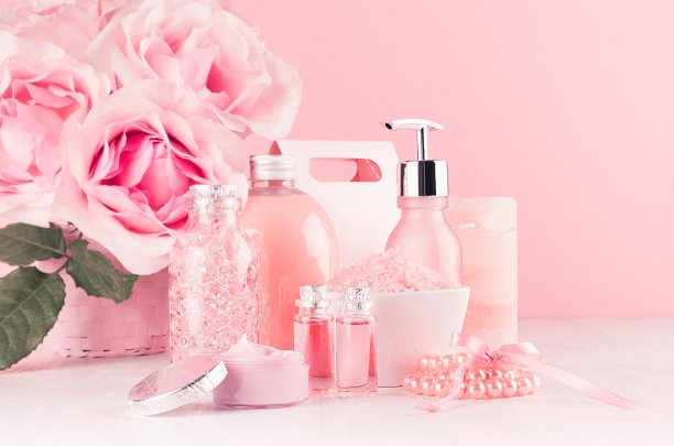 小女孩可爱的浴室内部用粉红色的花朵-皮肤化妆品，身体护理，配件，珍珠在柔软的白色木板上。图片下载