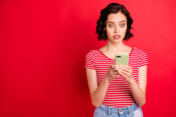 她的肖像，她漂亮迷人，漂亮可爱，担心，害怕，波浪式头发的十几岁的女孩空闲时间使用wi-fi可怕的新闻副本空间隔离在明亮生动的亮红色背景图片下载