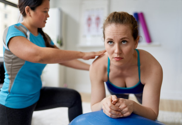 一位中国女性私人教练在一间明亮的医疗办公室里和一位迷人的金发客户健身图片下载