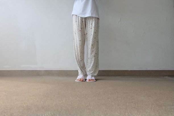 混凝土背景下的自拍拖鞋，俯视图。漂亮的年轻女子，穿着白色拖鞋和裤子。清暖的家凉鞋。图片下载