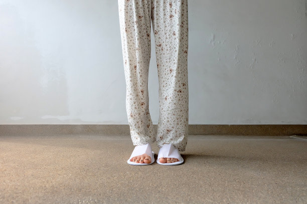 混凝土背景下的自拍拖鞋，俯视图。漂亮的年轻女子，穿着白色拖鞋和裤子。清暖的家凉鞋。图片下载