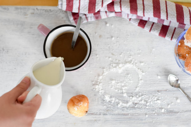 女人把牛奶倒进咖啡/拿铁/早餐桌上，开始一天的生活——图片图片下载