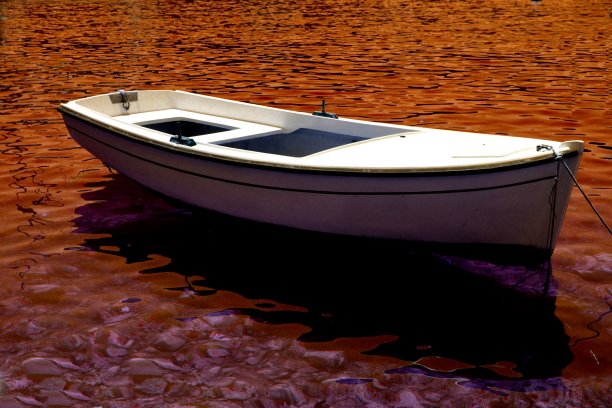 一艘白色的划艇在橙红色的水面上图片下载